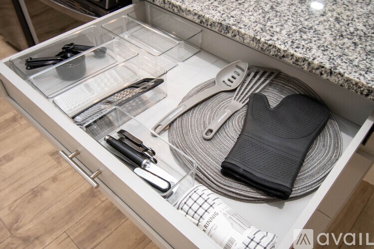 A drawer with utensils and a black napkin holder.