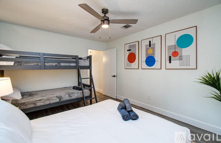 A room with a bunk bed, a ceiling fan, and three framed artworks on the wall.