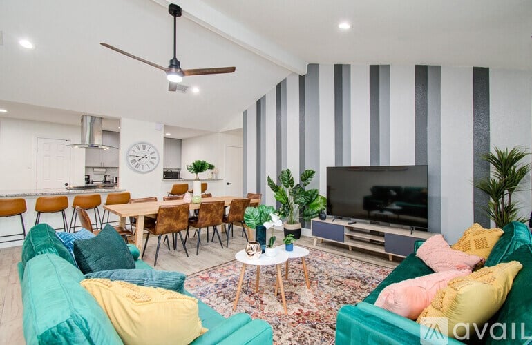 A living room with a green couch and a striped wallpaper.
