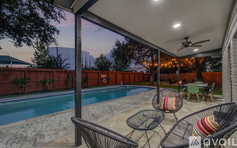A patio with a table and chairs overlooking a pool.