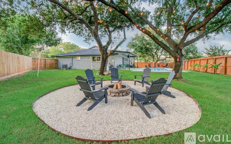 A backyard with a fire pit and chairs.