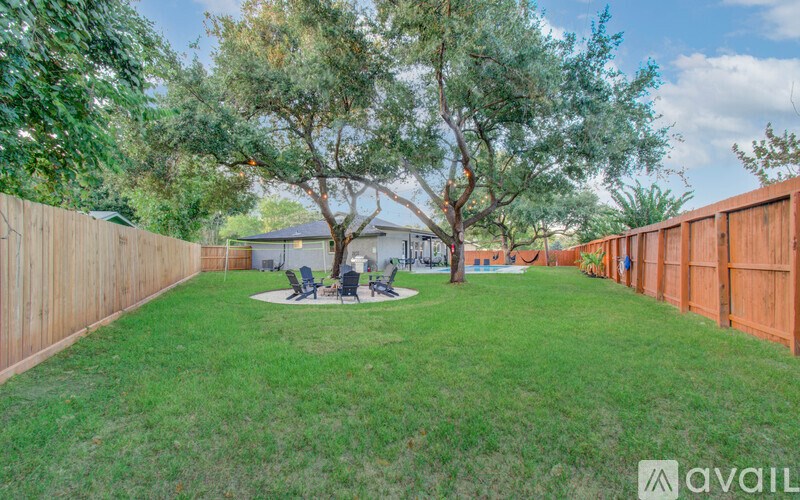 A backyard with a fence, a tree, and a picnic table.