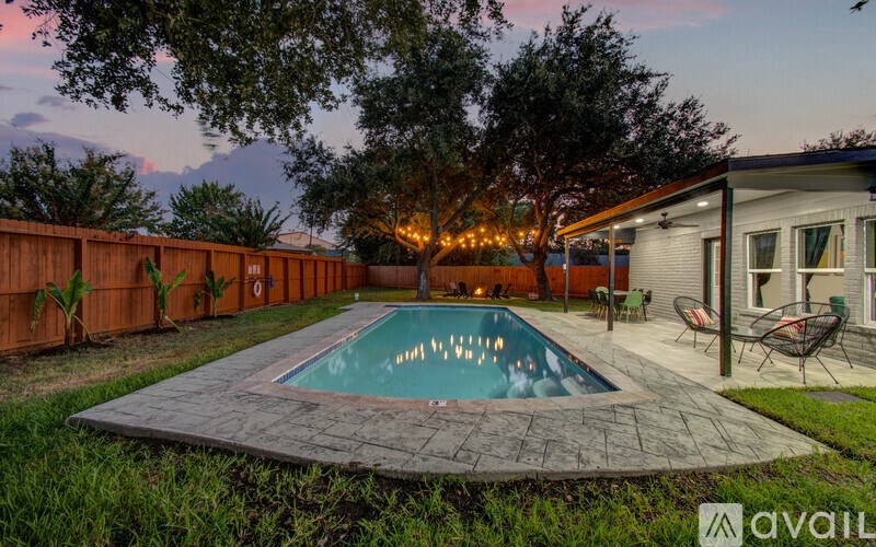 A backyard with a pool and patio furniture.