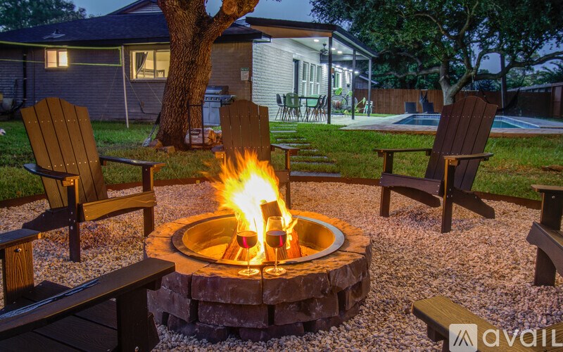 A fire pit in the middle of a gravel area with two chairs on either side.