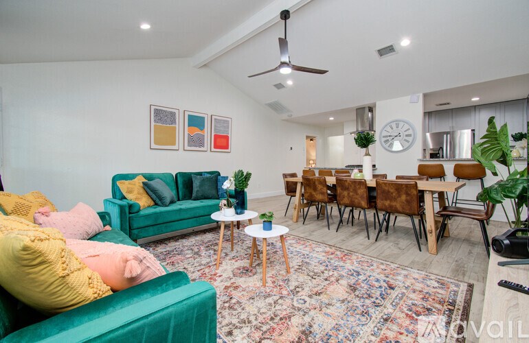 A living room with a green couch and a fan on the ceiling.