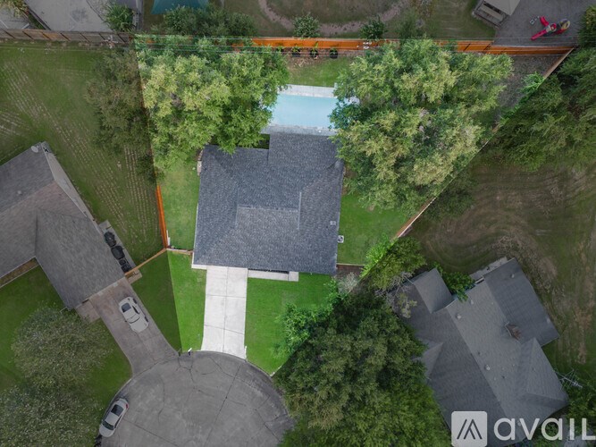 A bird's eye view of a residential area with a swimming pool and a road.