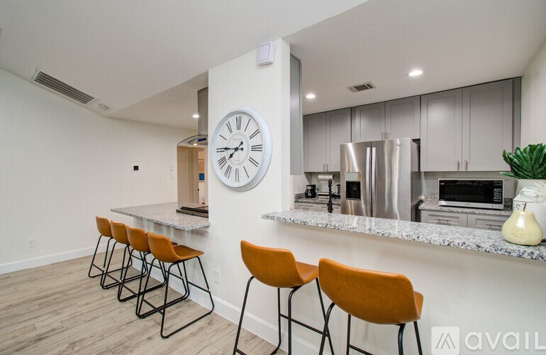 A kitchen with a bar area and a clock on the wall.