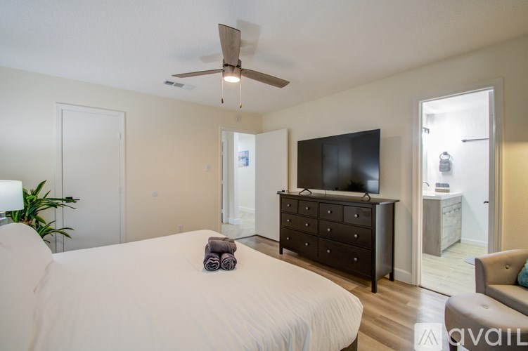 A bedroom with a bed, dresser, and ceiling fan.