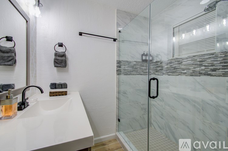 A bathroom with a glass shower door and a white sink.