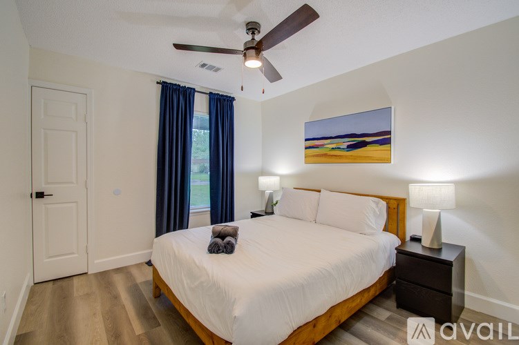 A bedroom with a bed, nightstand, and a painting of a beach scene on the wall.