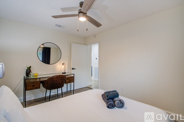 A bedroom with a bed, desk, chair, and mirror.