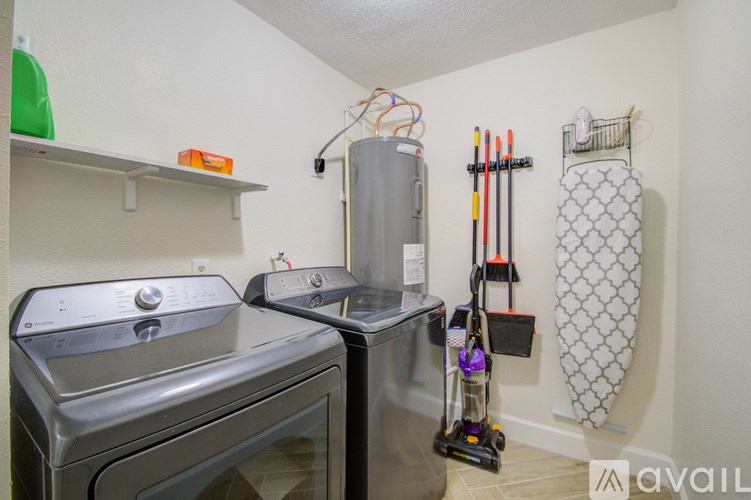 A small laundry room with a washer and dryer, a vacuum cleaner, and a mop.