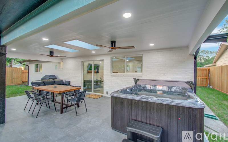 A patio with a hot tub and a table with chairs.