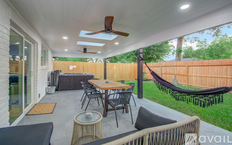 A patio with a table, chairs, and a hammock.