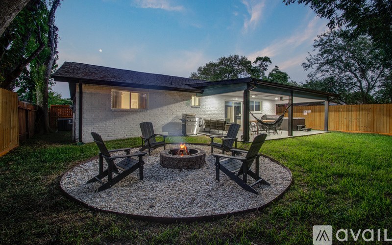 A backyard with a fire pit and chairs.