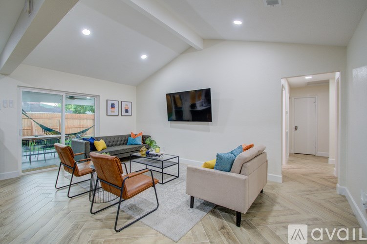 A living room with a grey couch, a coffee table, and a television mounted on the wall.