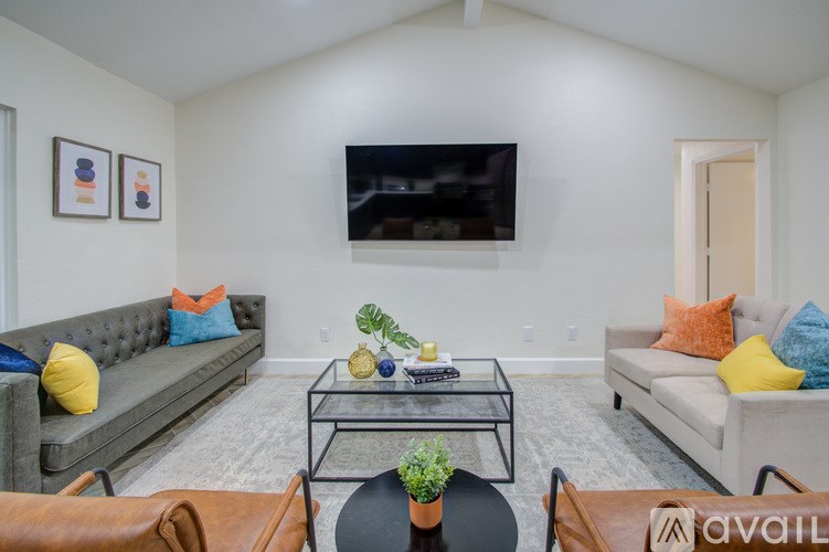 A living room with a grey couch, a black coffee table, and a flat screen TV mounted on the wall.