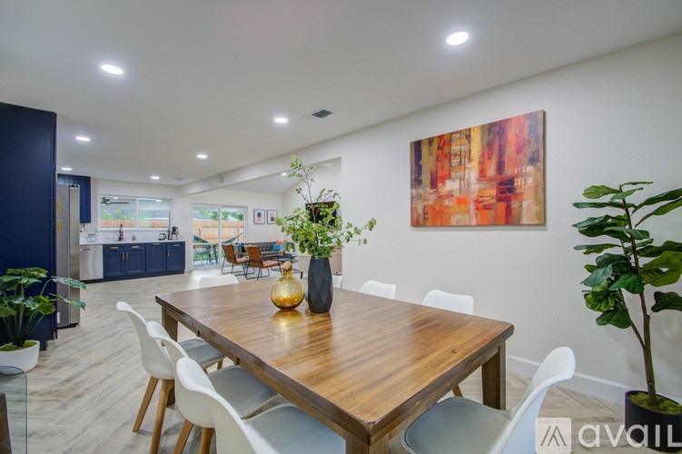 A dining room with a wooden table and white chairs.