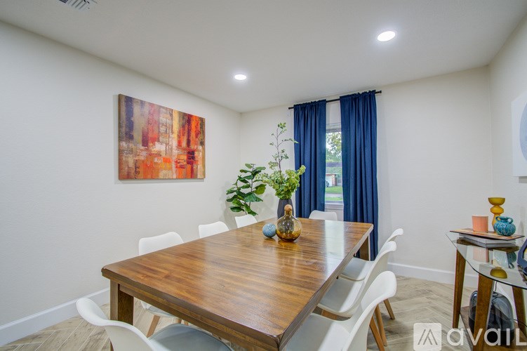 A dining room with a wooden table and white chairs.