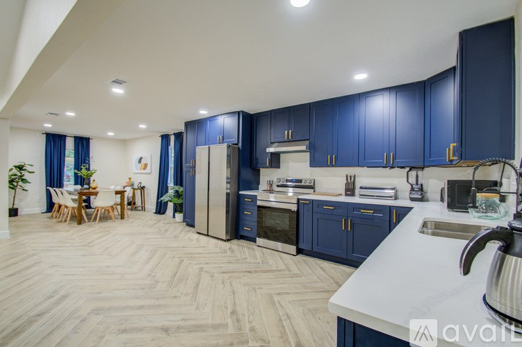 A spacious kitchen with blue cabinets and a wooden floor.