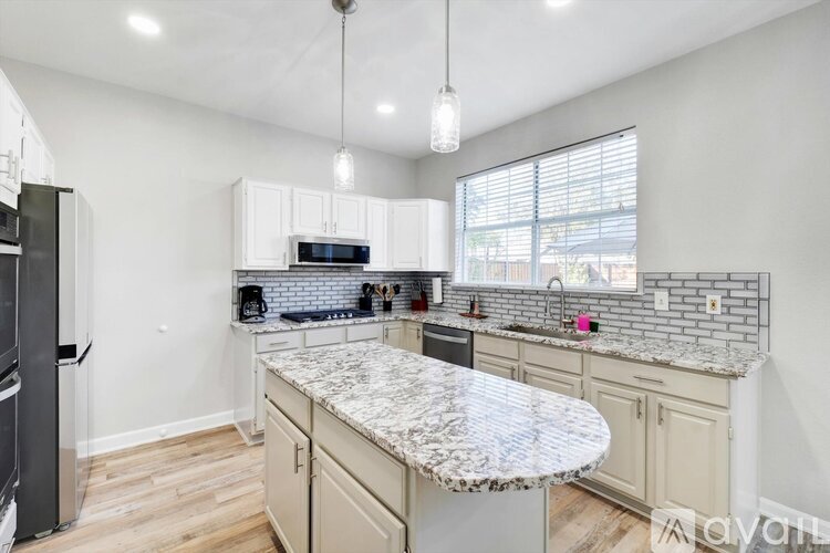 A kitchen with a granite countertop and a refrigerator on the left.