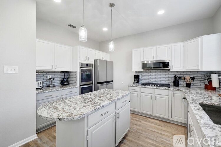 A kitchen with white cabinets and a marble island.