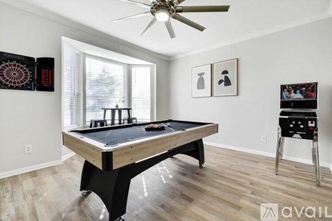 A pool table in a room with a ceiling fan and a dartboard on the wall.