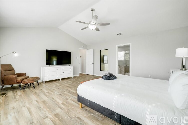 A bedroom with a large bed, a chair, a TV, and a dresser.