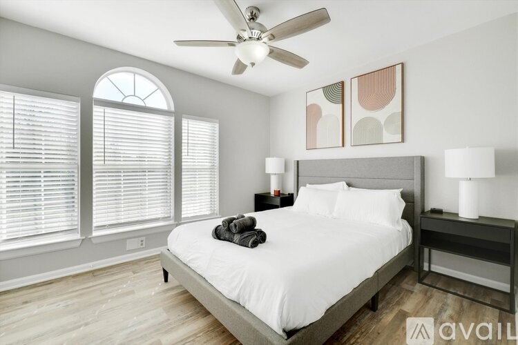 A bedroom with a bed, a ceiling fan, and a window with blinds.
