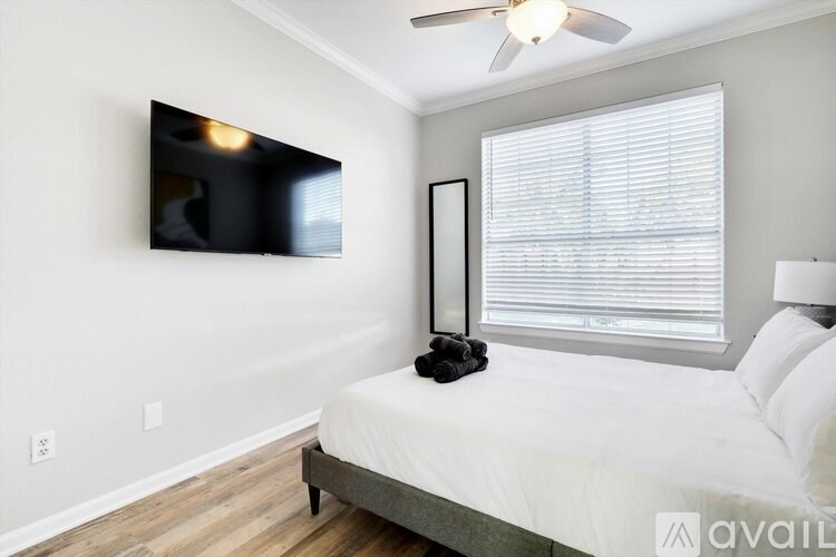 A bedroom with a bed, a ceiling fan, and a window with blinds.