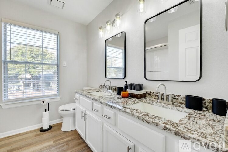 A white bathroom with a marble countertop and a large mirror.
