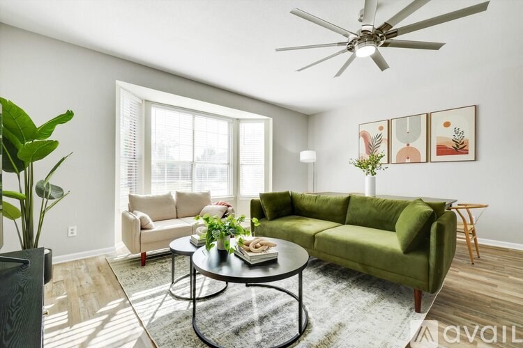 A living room with a green sofa, a coffee table, and a ceiling fan.