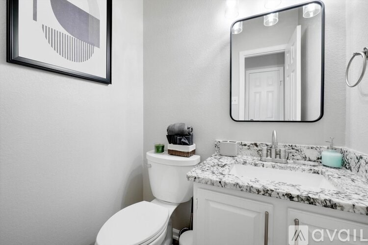 A bathroom with a toilet, sink, and mirror.