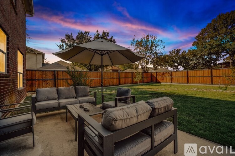 A patio with a table and chairs under an umbrella.