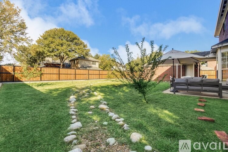 A backyard with a lawn, a pathway, and a fence.