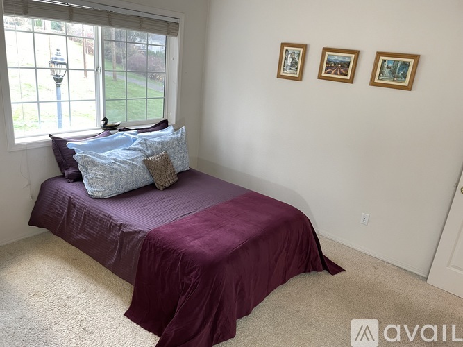 A bedroom with a bed covered in a purple sheet and two pillows.