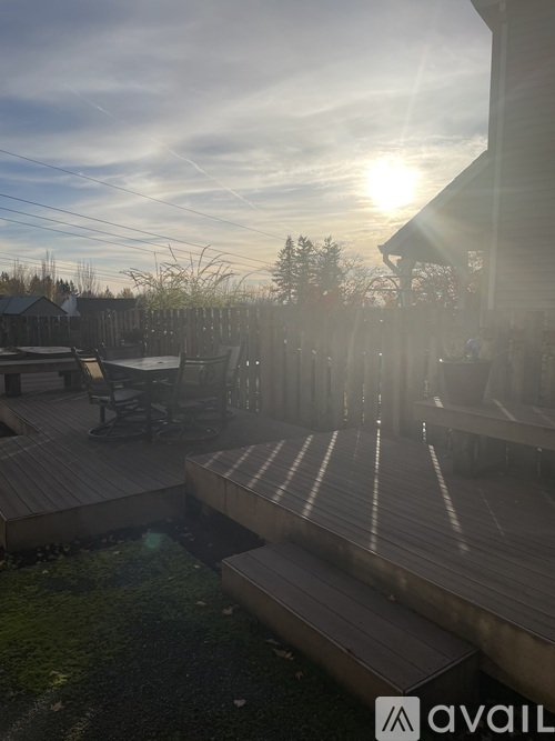 A sunny backyard with a wooden deck and a hot tub.