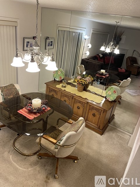 A living room with a glass table and a wooden cabinet.