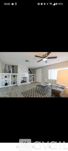 A modern living room with a ceiling fan and a large window.