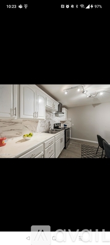 A kitchen with white cabinets and a black chair.