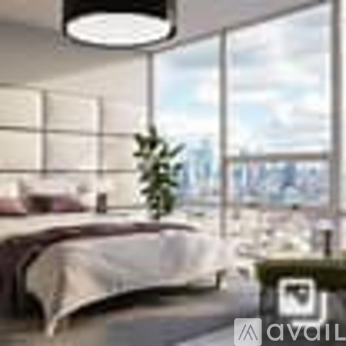 A bedroom with a large bed and a plant on the windowsill.