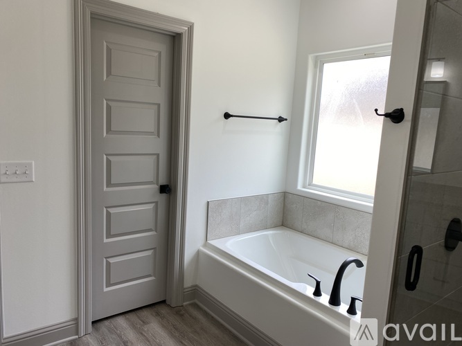 A bathroom with a white door, a bathtub, and a window.