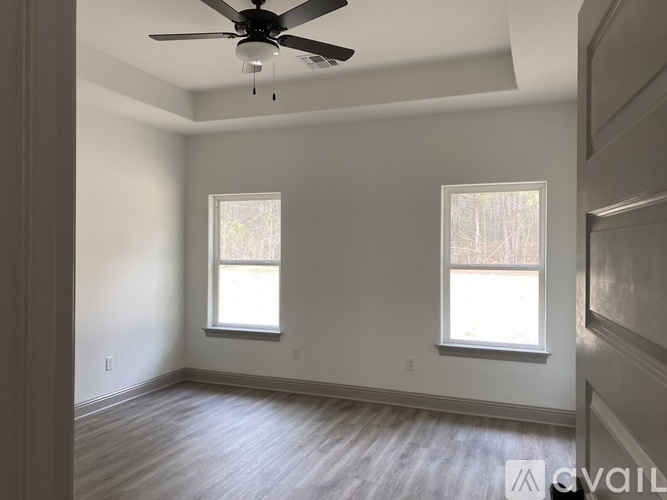 A room with a ceiling fan and two windows.
