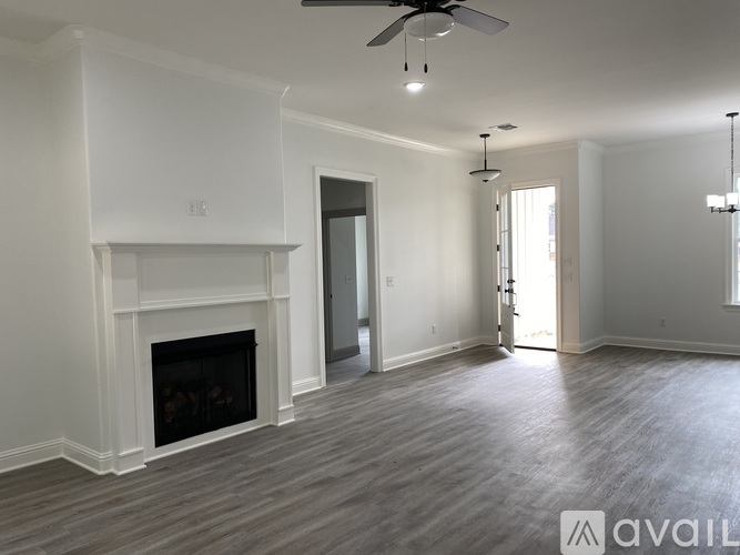 A spacious living room with a fireplace and a ceiling fan.