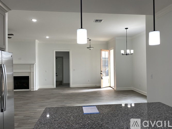 A modern kitchen with a refrigerator on the left and a living area with a fireplace in the background.