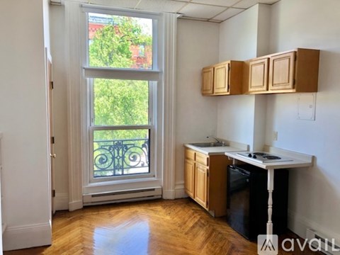 A kitchen with wooden cabinets and a window overlooking a balcony.
