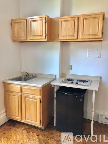 A kitchen with wooden cabinets and a black trash can.