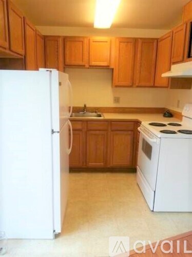 A kitchen with white appliances and wooden cabinets.