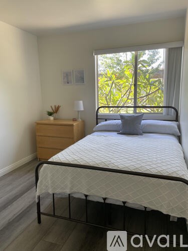 A bedroom with a bed, nightstand, and window.