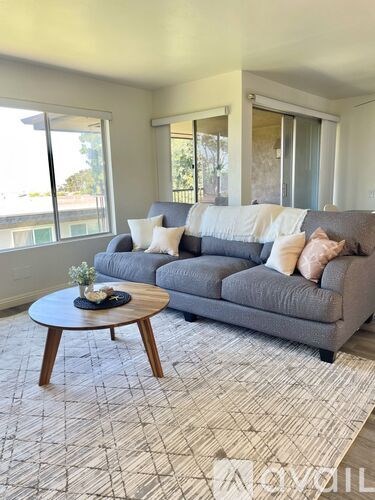 A living room with a grey couch and a round wooden coffee table.